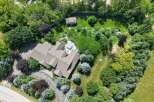 Discover this stunning property featuring a spacious home with a multi-faceted roof, surrounded by lush greenery and mature trees.