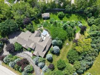 Discover this stunning property featuring a spacious home with a multi-faceted roof, surrounded by lush greenery and mature trees.