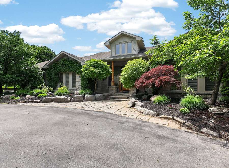 Discover this stunning home featuring a natural stone facade and lush landscaping, creating an inviting curb appeal.