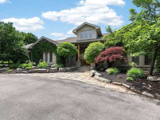 Discover this stunning home featuring a natural stone facade and lush landscaping, creating an inviting curb appeal.