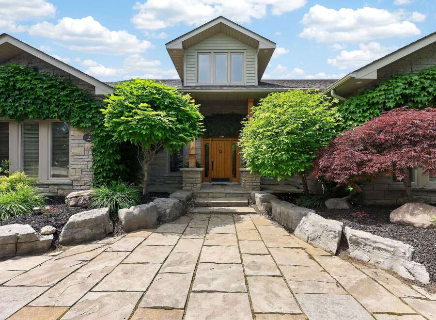 Discover this stunning home featuring a natural stone facade and lush landscaping.