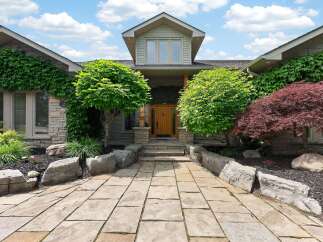 Discover this stunning home featuring a natural stone facade and lush landscaping.