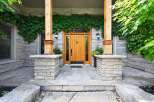 Enhance your home's curb appeal with this charming entryway, featuring a beautiful wooden door framed by natural stone and lush greenery.