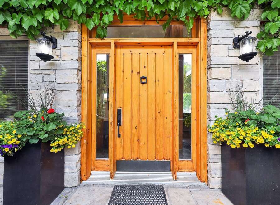 Enhance your home's curb appeal with this stunning entryway, featuring a warm, natural wood door complemented by elegant stone accents.