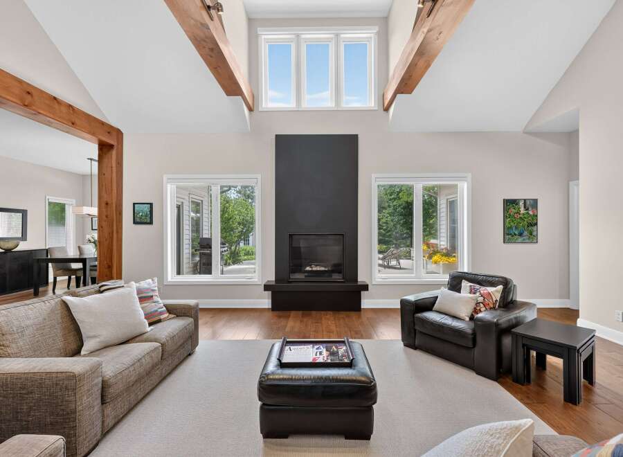 Experience luxury living in this stunning great room, featuring a dramatic vaulted ceiling with exposed wooden beams and a sleek, modern fireplace.