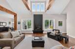 Experience luxury living in this stunning great room, featuring a dramatic vaulted ceiling with exposed wooden beams and a sleek, modern fireplace.