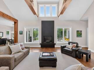 Experience luxury living in this stunning great room, featuring a dramatic vaulted ceiling with exposed wooden beams and a sleek, modern fireplace.