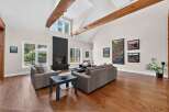 Experience luxurious living in this stunning great room, featuring a dramatic vaulted ceiling with exposed wooden beams and a modern black fireplace as the focal point.