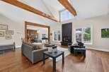 Experience luxurious living in this stunning great room, featuring soaring vaulted ceilings with exposed wooden beams and a modern black fireplace as the focal point.