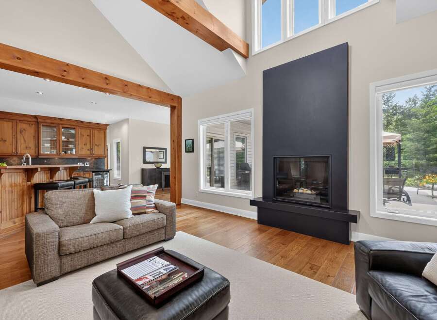Experience luxury living in this stunning home featuring a grand living room with a soaring ceiling and exposed wooden beams.