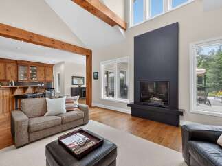 Experience luxury living in this stunning home featuring a grand living room with a soaring ceiling and exposed wooden beams.
