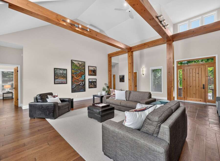 Experience rustic elegance in this spacious living room featuring soaring vaulted ceilings with exposed wooden beams and a striking stone fireplace.