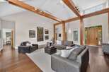 Experience rustic elegance in this spacious living room featuring soaring vaulted ceilings with exposed wooden beams and a striking stone fireplace.