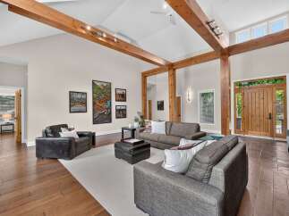 Experience rustic elegance in this spacious living room featuring soaring vaulted ceilings with exposed wooden beams and a striking stone fireplace.
