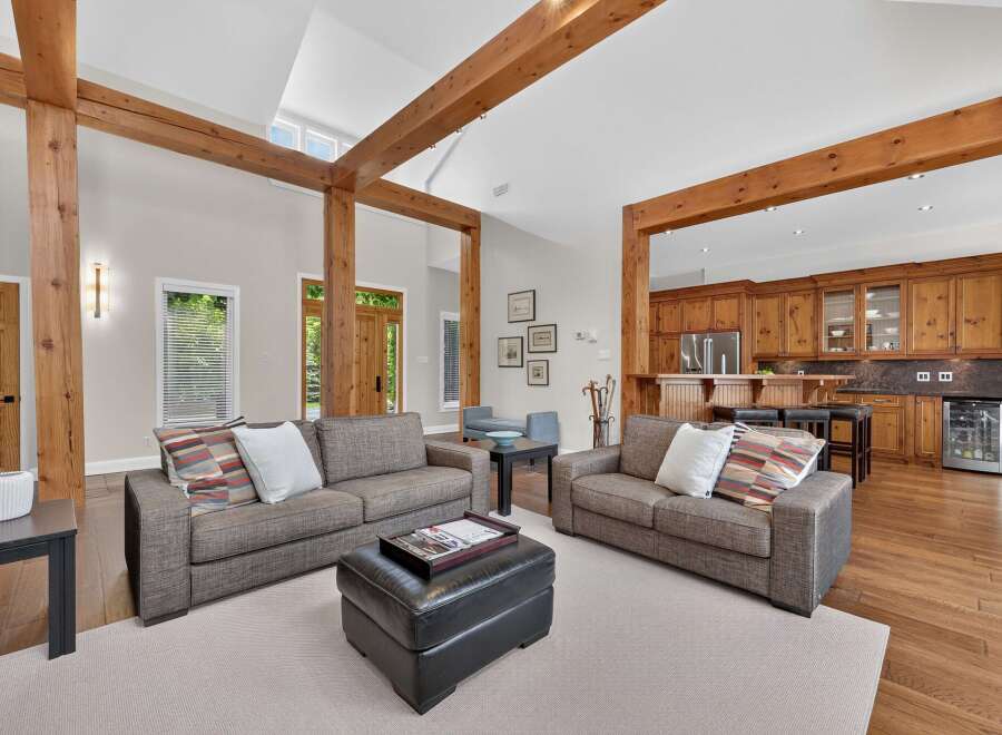 Experience rustic charm and modern comfort in this spacious living area, featuring exposed wooden beams and a seamless flow into a well-appointed kitchen.