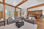 Experience rustic charm and modern comfort in this spacious living area, featuring exposed wooden beams and a seamless flow into a well-appointed kitchen.
