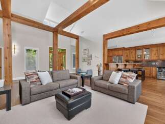 Experience rustic charm and modern comfort in this spacious living area, featuring exposed wooden beams and a seamless flow into a well-appointed kitchen.