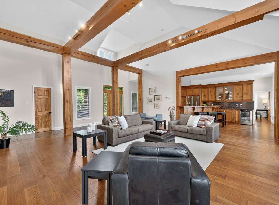 Experience rustic charm and modern comfort in this spacious living area, featuring exposed wooden beams and a vaulted ceiling.