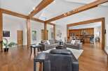 Experience rustic charm and modern comfort in this spacious living area, featuring exposed wooden beams and a vaulted ceiling.