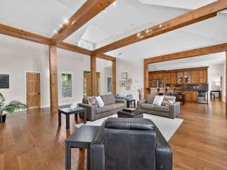 Experience rustic charm and modern comfort in this spacious living area, featuring exposed wooden beams and a vaulted ceiling.
