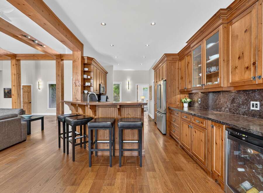 Experience rustic charm in this spacious kitchen featuring warm wooden cabinetry and exposed beams.
