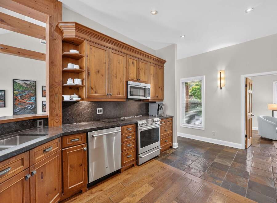 This stunning kitchen boasts custom wood cabinetry, a sleek stainless steel appliance suite including a microwave and dishwasher, and a durable granite countertop.