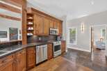 This stunning kitchen boasts custom wood cabinetry, a sleek stainless steel appliance suite including a microwave and dishwasher, and a durable granite countertop.