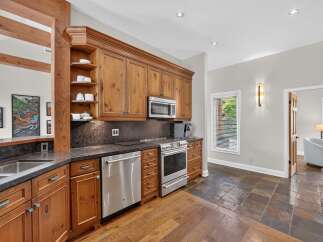 This stunning kitchen boasts custom wood cabinetry, a sleek stainless steel appliance suite including a microwave and dishwasher, and a durable granite countertop.