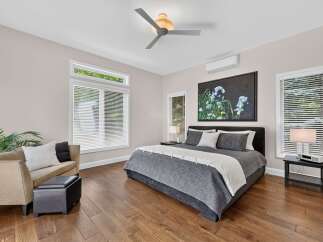 Experience modern comfort in this spacious bedroom, featuring a king-sized bed with luxurious grey bedding and a striking floral art piece above.