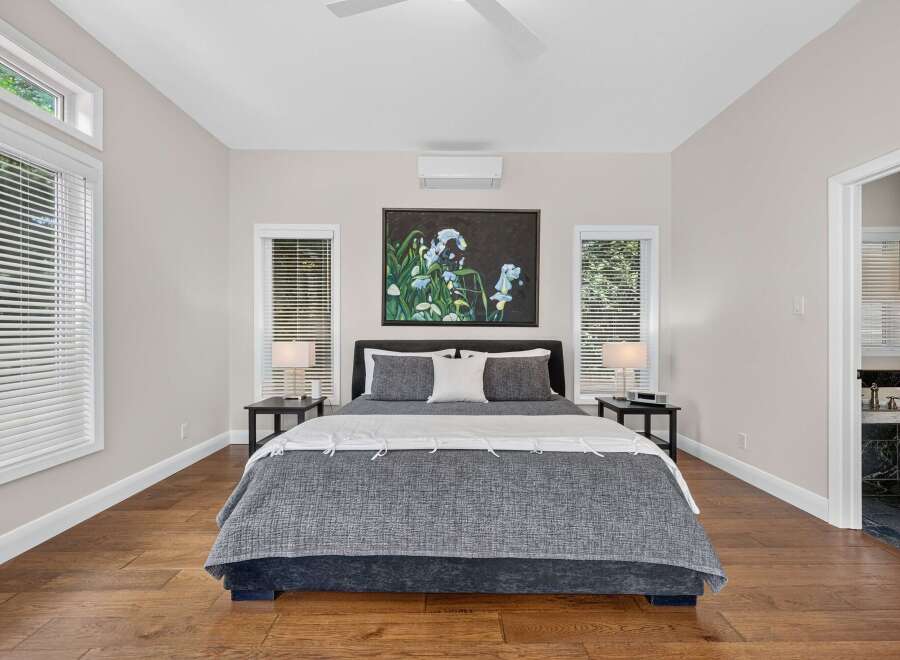 Experience ultimate comfort in this beautifully appointed bedroom, featuring a plush king-size bed adorned with luxurious grey and white linens.