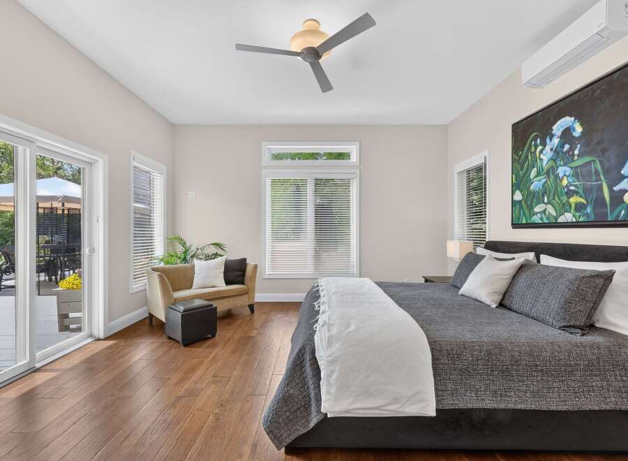 Experience luxurious living in this spacious master bedroom, featuring a king-sized bed adorned with plush pillows and a cozy throw.