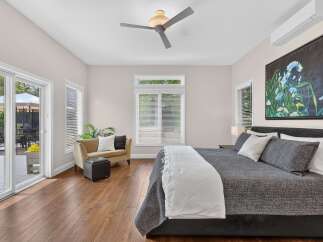 Experience luxurious living in this spacious master bedroom, featuring a king-sized bed adorned with plush pillows and a cozy throw.
