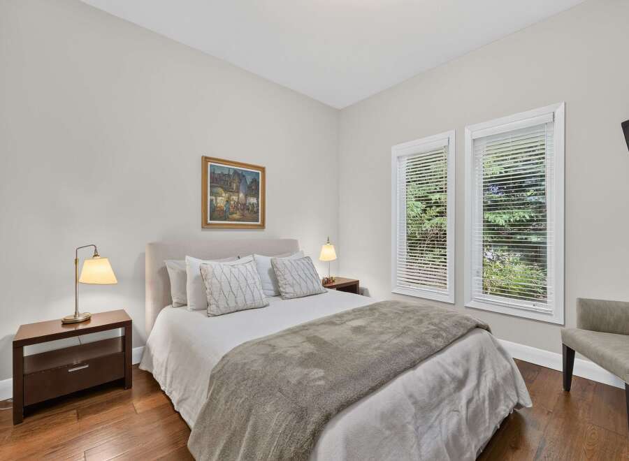 Experience tranquility in this inviting bedroom, featuring a plush bed adorned with decorative pillows and a cozy throw blanket.