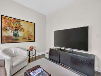 This living room features a large flat-screen TV mounted above a sleek, dark wood media console, perfect for entertainment.