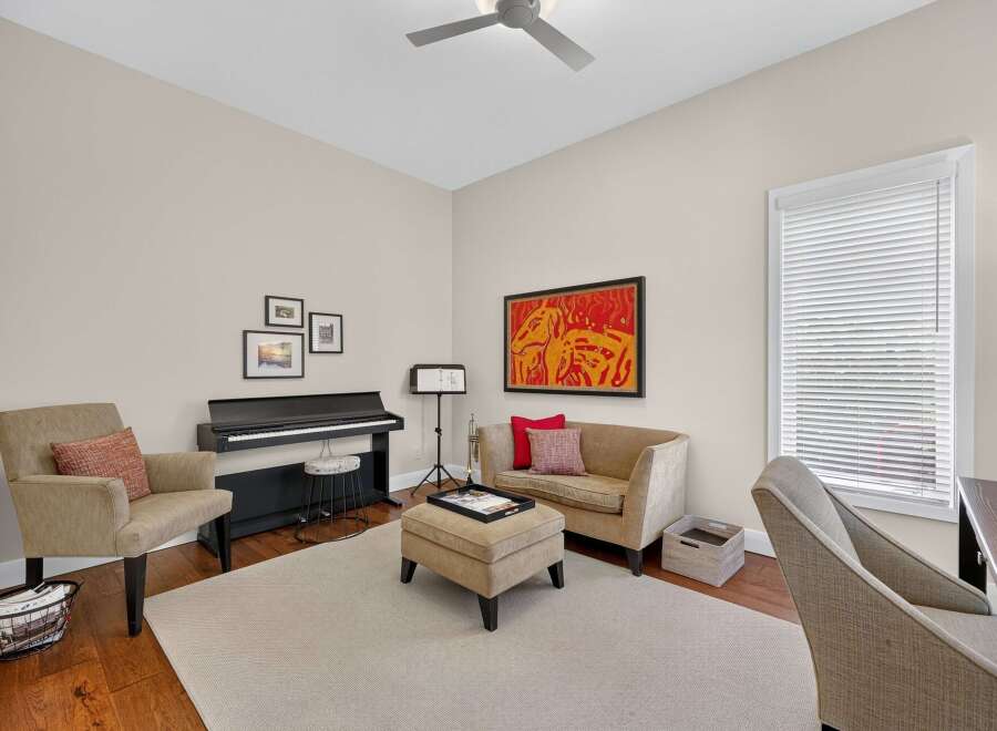 This inviting room features a digital piano, perfect for aspiring musicians, complemented by a comfortable seating area with a loveseat and armchair.