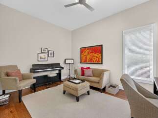 This inviting room features a digital piano, perfect for aspiring musicians, complemented by a comfortable seating area with a loveseat and armchair.