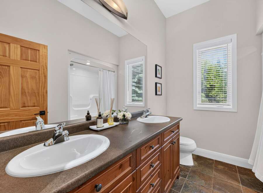 This spacious bathroom features a double vanity with ample counter space and storage, perfect for any household.