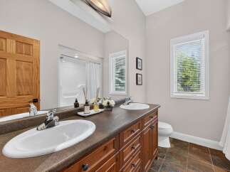 This spacious bathroom features a double vanity with ample counter space and storage, perfect for any household.