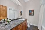 This bright and clean bathroom features a spacious vanity with a granite countertop and a white undermount sink.