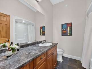 This bright and clean bathroom features a spacious vanity with a granite countertop and a white undermount sink.