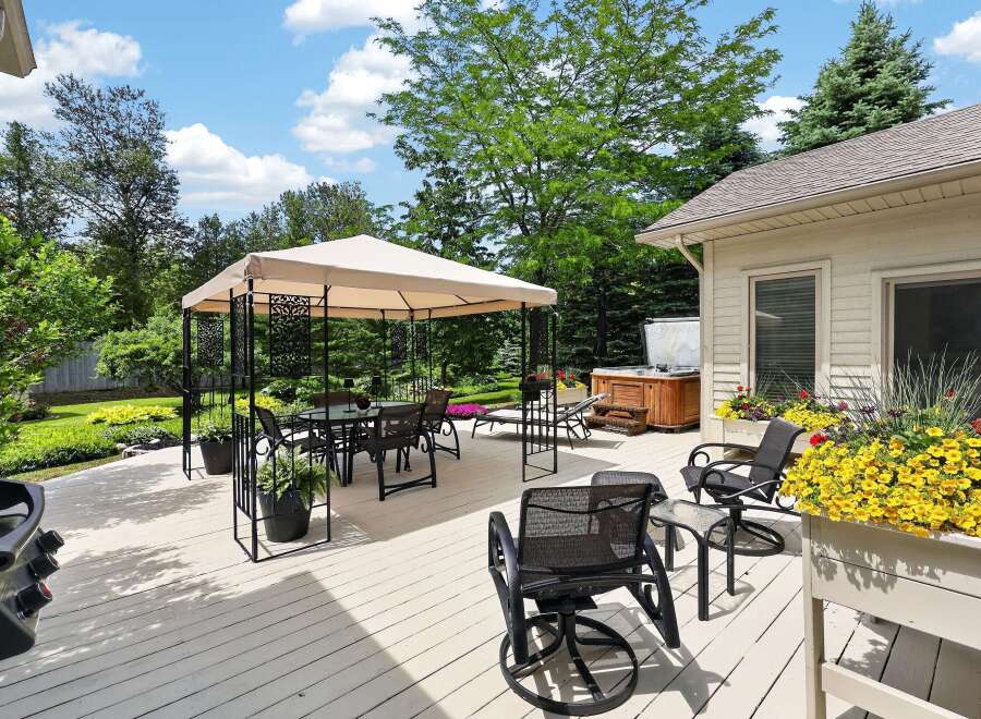 Enjoy outdoor living at its finest on this expansive deck, featuring a covered dining area, a luxurious hot tub, and comfortable seating.
