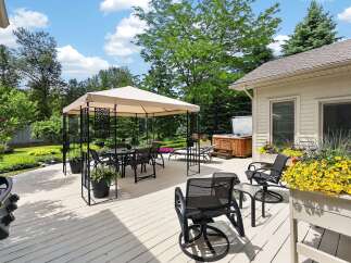 Enjoy outdoor living at its finest on this expansive deck, featuring a covered dining area, a luxurious hot tub, and comfortable seating.