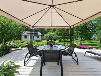 Enjoy outdoor living under this elegant gazebo, featuring a glass-top dining table and four chairs perfect for al fresco meals.