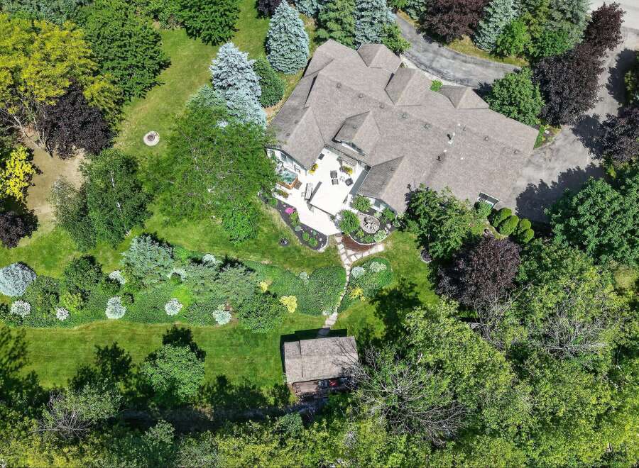 Experience luxurious outdoor living with this stunning aerial view showcasing a spacious deck, a relaxing hot tub, and meticulously landscaped gardens.