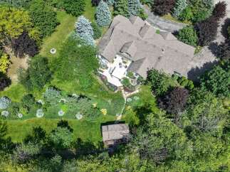 Experience luxurious outdoor living with this stunning aerial view showcasing a spacious deck, a relaxing hot tub, and meticulously landscaped gardens.