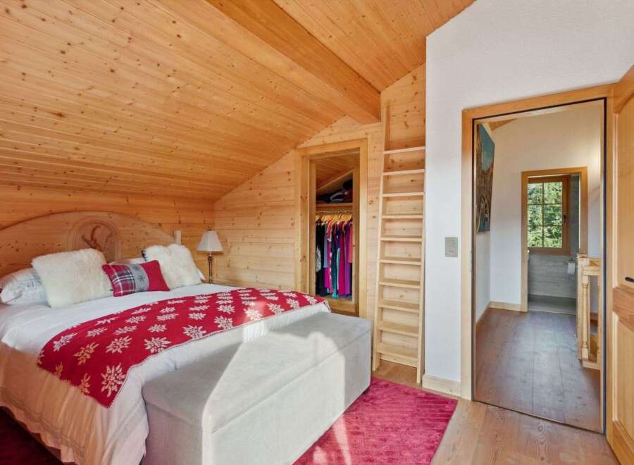 Experience rustic charm in this cozy bedroom featuring a wooden-paneled ceiling and walls, creating a warm and inviting atmosphere.