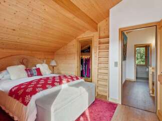 Experience rustic charm in this cozy bedroom featuring a wooden-paneled ceiling and walls, creating a warm and inviting atmosphere.