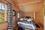 Experience cozy mountain living in this charming chalet bedroom, featuring a plush faux fur throw and warm wood paneling throughout.