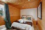 Experience cozy mountain living in this charming bedroom featuring warm wood-paneled walls and ceiling.