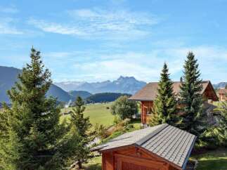 Experience serene mountain living in this charming wooden chalet, nestled amidst lush greenery and offering breathtaking views of snow-capped peaks.
